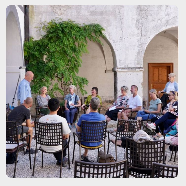 Niall Kelly giving a talk in Monastery courtyard, audience sitting in a circle